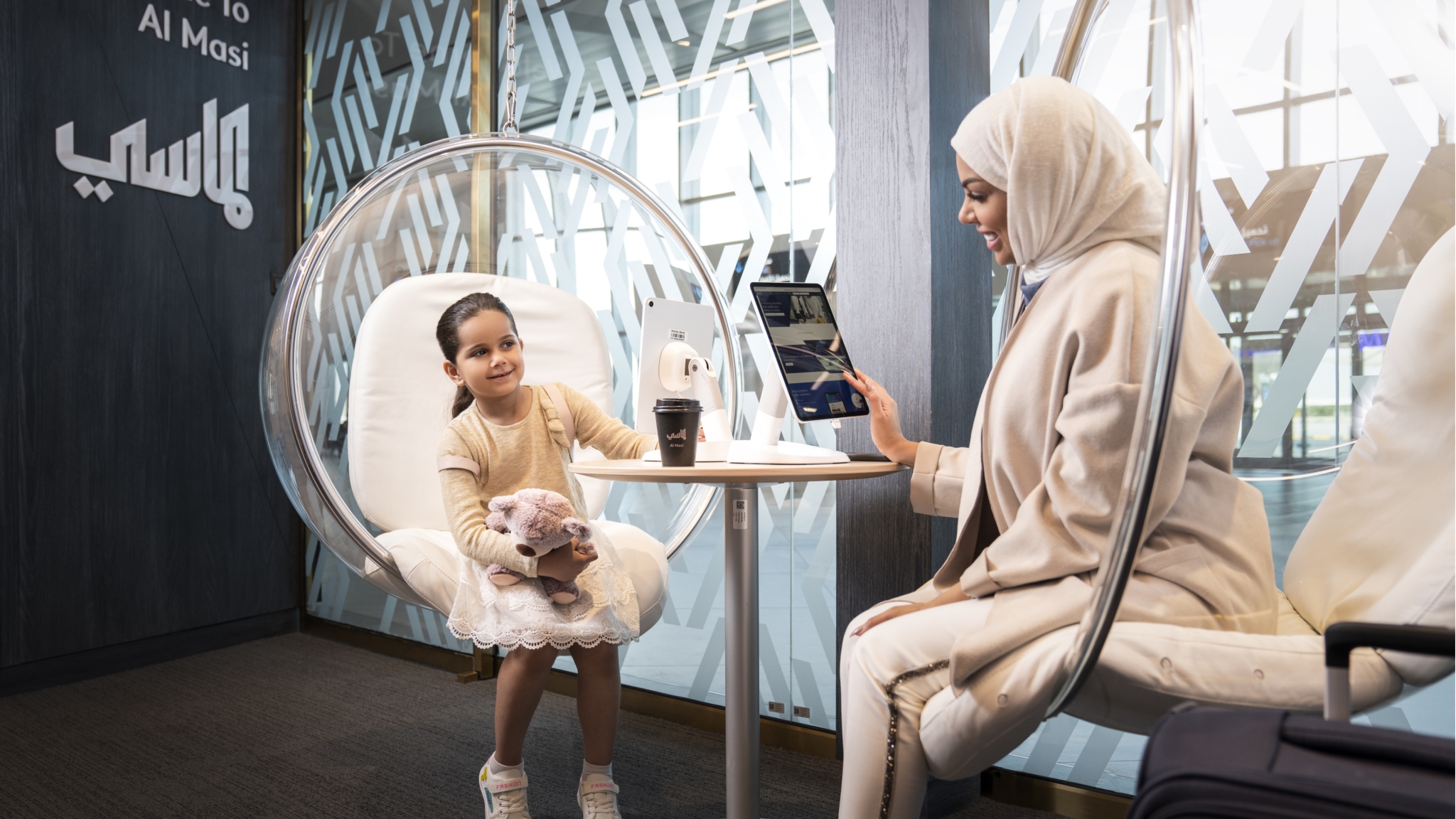 Mother and daughter using customer tablets in the bank's lounge area.